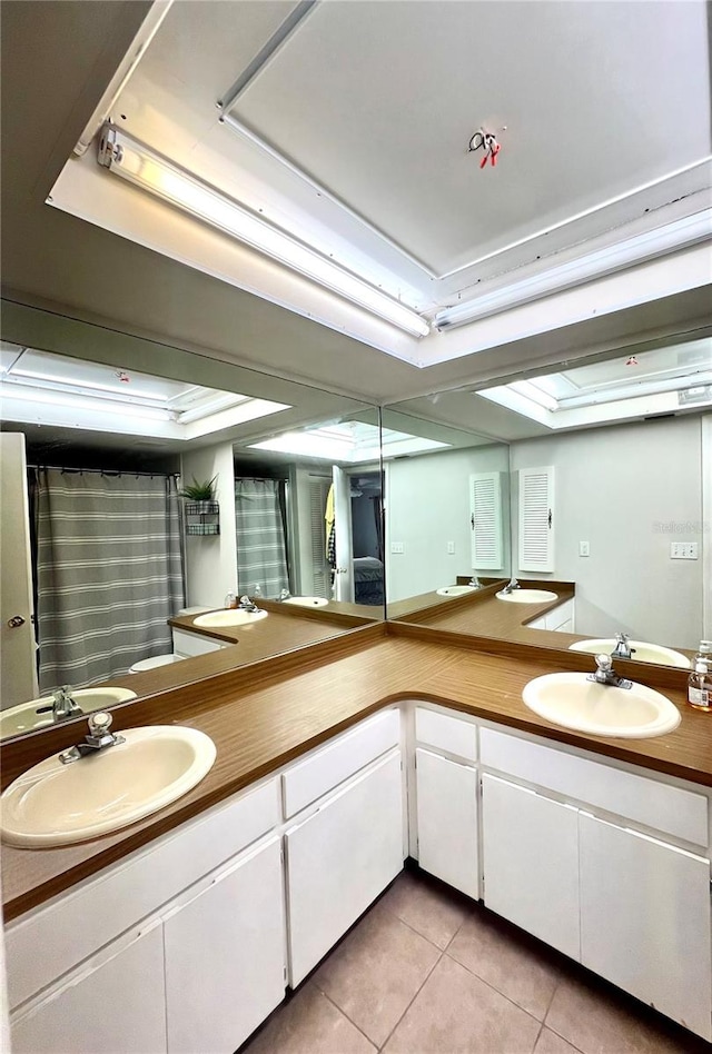 bathroom with tile patterned flooring, vanity, and a tray ceiling