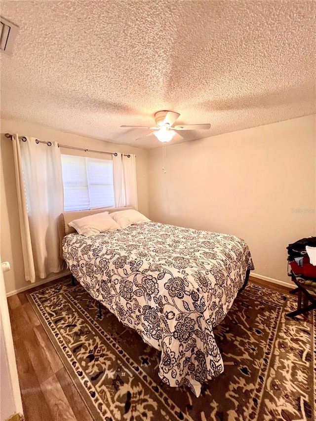 bedroom featuring ceiling fan, dark wood-type flooring, and a textured ceiling