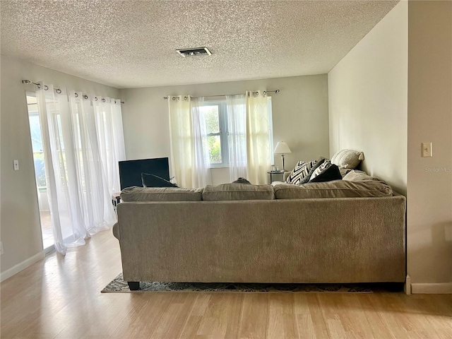 living room with a textured ceiling and light hardwood / wood-style flooring