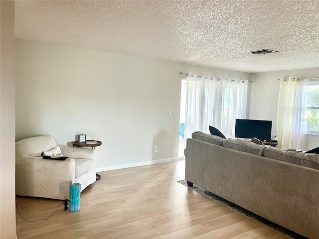 living room with a textured ceiling and light wood-type flooring