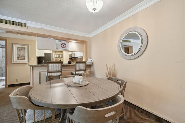 dining space with a textured ceiling, dark carpet, and ornamental molding