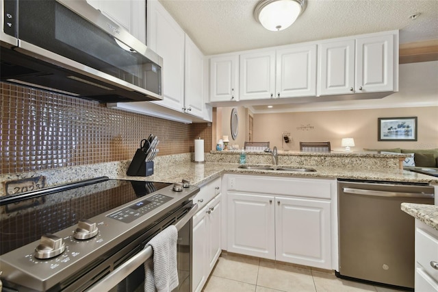 36750 US Highway 19 N Unit 19219, Palm Harbor, FL 34684 - kitchen with stainless steel appliances, a sink, white cabinets, light tile patterned floors, and light stone countertops