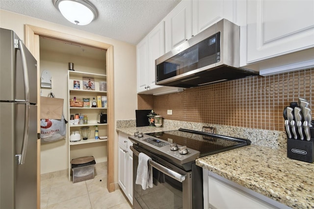 kitchen featuring white cabinets, a textured ceiling, stainless steel appliances, and tasteful backsplash