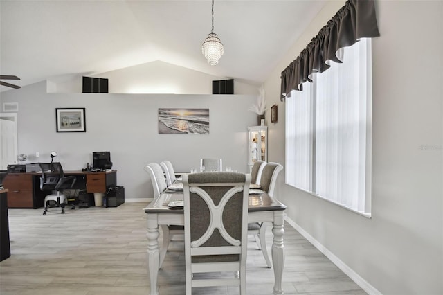 dining room with a wealth of natural light, light wood-type flooring, baseboards, and vaulted ceiling