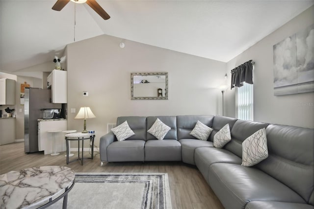 living area featuring a ceiling fan, vaulted ceiling, and light wood-style floors