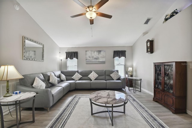 living area with visible vents, high vaulted ceiling, light wood finished floors, baseboards, and ceiling fan