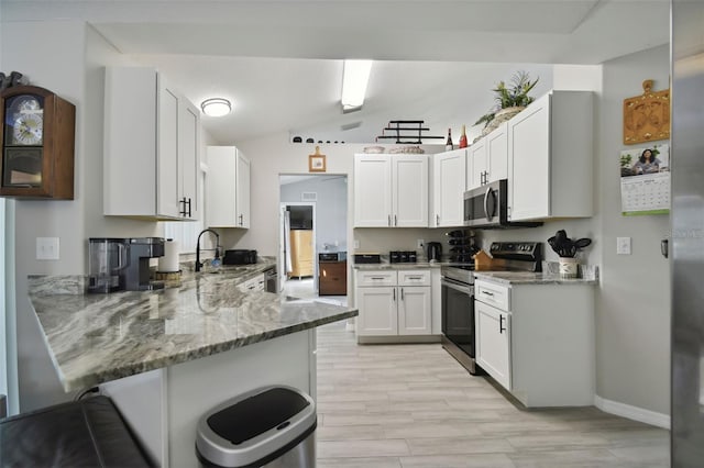 kitchen with light stone counters, stainless steel appliances, a kitchen bar, and a peninsula