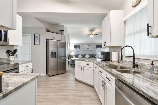 kitchen featuring a sink, open floor plan, white cabinetry, and stainless steel appliances