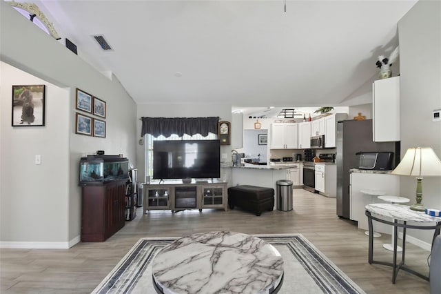 living room featuring visible vents, baseboards, lofted ceiling, and light wood-style flooring