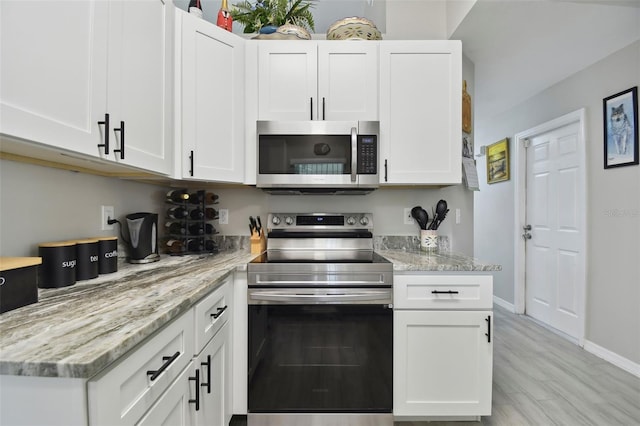 kitchen featuring light stone counters, baseboards, light wood finished floors, appliances with stainless steel finishes, and white cabinetry