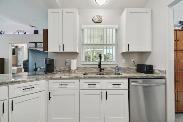 kitchen with a sink, light stone countertops, stainless steel dishwasher, and white cabinetry