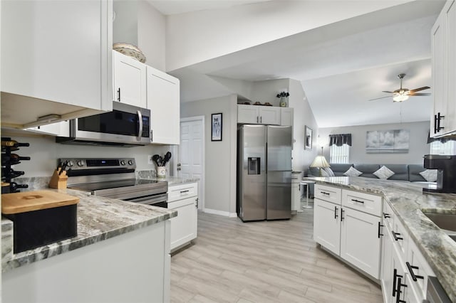 kitchen with light stone counters, appliances with stainless steel finishes, white cabinets, and ceiling fan