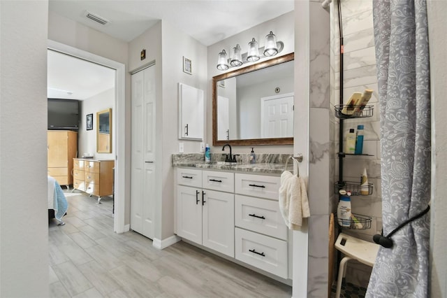 bathroom with visible vents, ensuite bath, wood finished floors, and vanity