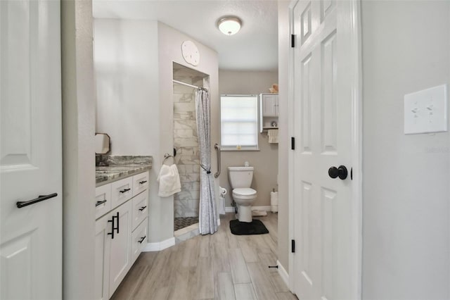 full bath with a shower stall, baseboards, toilet, wood finished floors, and vanity