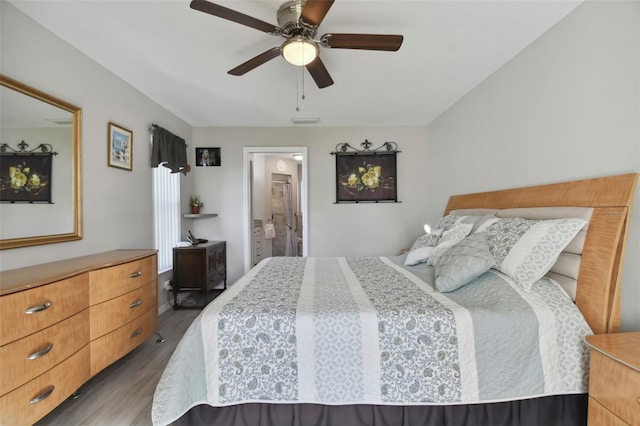 bedroom featuring a ceiling fan, ensuite bath, wood finished floors, and visible vents