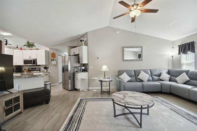 living area with baseboards, light wood finished floors, ceiling fan, and vaulted ceiling