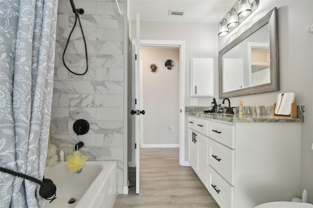 full bath featuring visible vents, wood finished floors, shower / bath combination with curtain, baseboards, and vanity