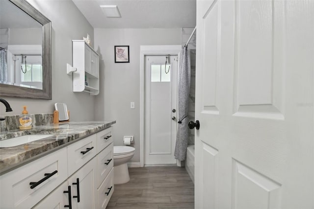 full bathroom featuring visible vents, toilet, shower / tub combo, wood finished floors, and vanity