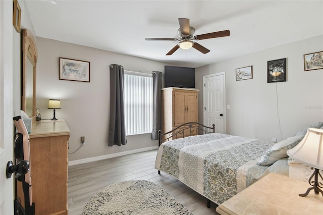 bedroom featuring light wood finished floors, a ceiling fan, and baseboards