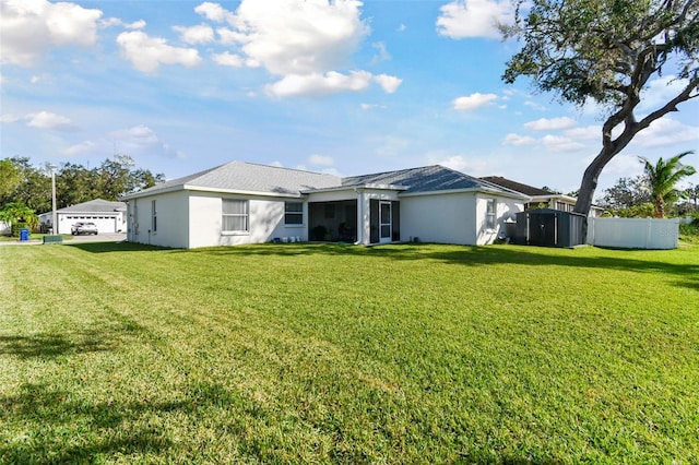 back of property featuring stucco siding, a detached garage, a yard, and fence