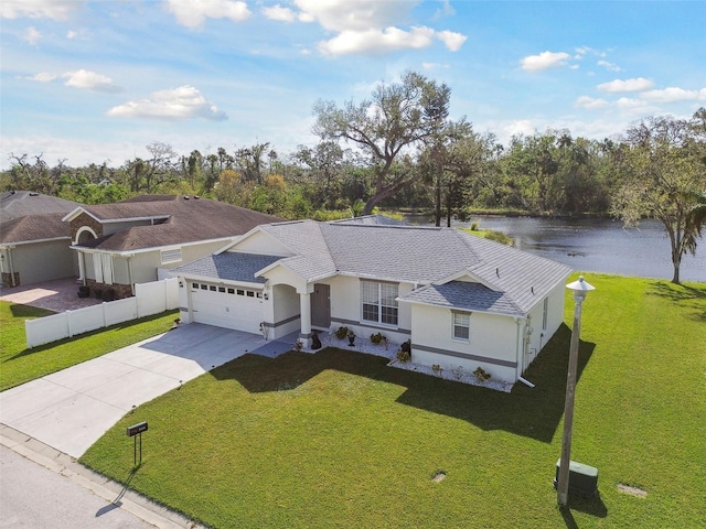 view of front of house with a water view, an attached garage, concrete driveway, and a front lawn