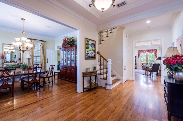 foyer featuring a chandelier, wood-type flooring, and ornamental molding