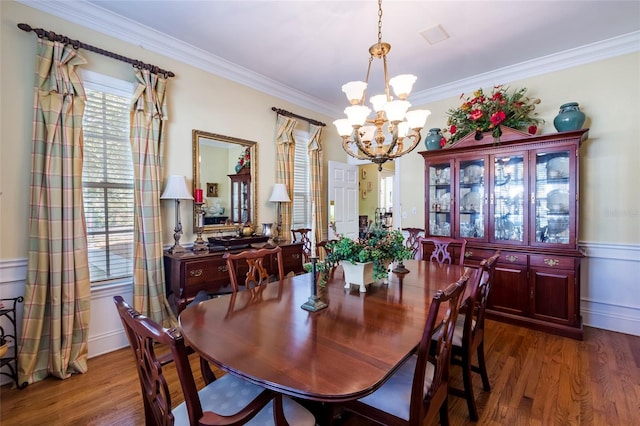 dining space with dark hardwood / wood-style flooring, crown molding, and an inviting chandelier