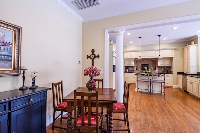 dining area with light hardwood / wood-style floors, ornate columns, and crown molding