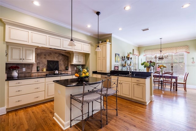 kitchen featuring backsplash, cream cabinets, a center island, and pendant lighting