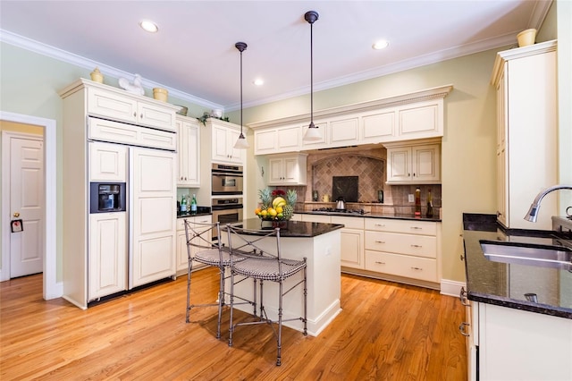 kitchen featuring appliances with stainless steel finishes, crown molding, pendant lighting, and sink