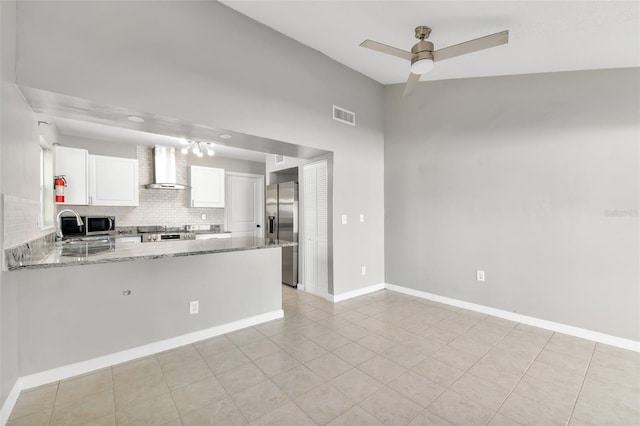 kitchen featuring white cabinetry, light stone countertops, wall chimney exhaust hood, kitchen peninsula, and appliances with stainless steel finishes