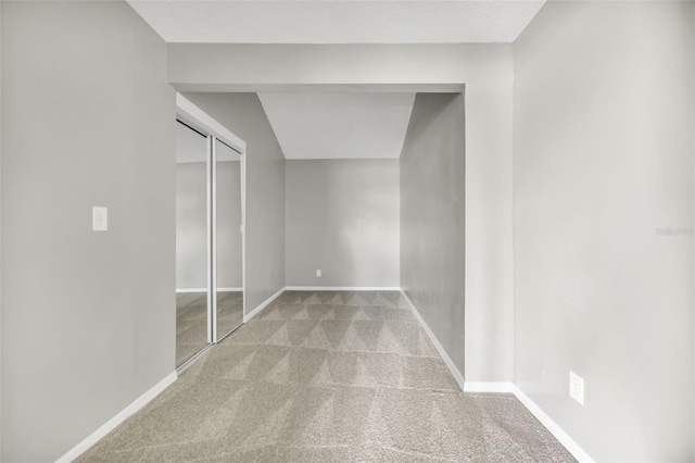 unfurnished bedroom with vaulted ceiling, light colored carpet, and a closet