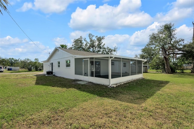 back of house with central AC, a lawn, and a sunroom