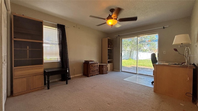 office area with a textured ceiling, ceiling fan, and light carpet