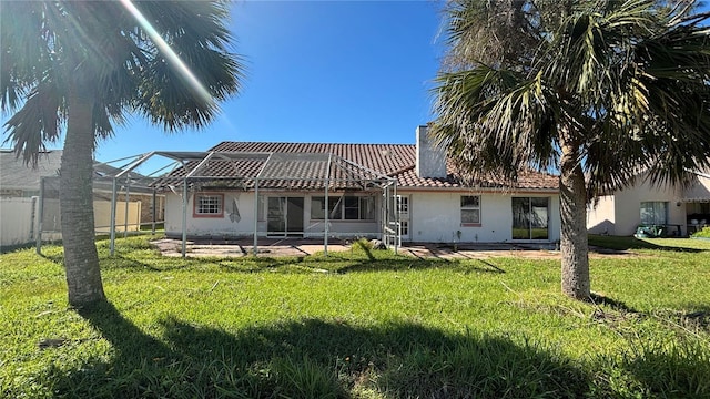 back of property with a yard, glass enclosure, and a patio area