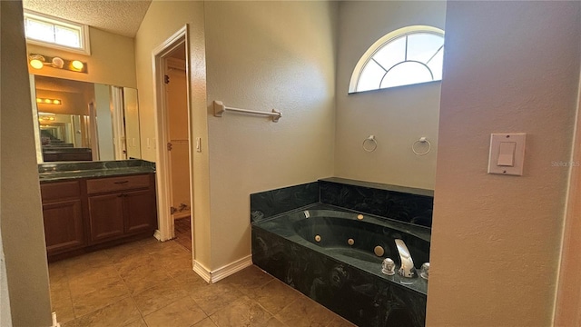 bathroom with vanity, a bath, and a textured ceiling