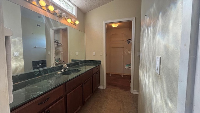 bathroom featuring tile patterned flooring, vanity, a textured ceiling, and vaulted ceiling