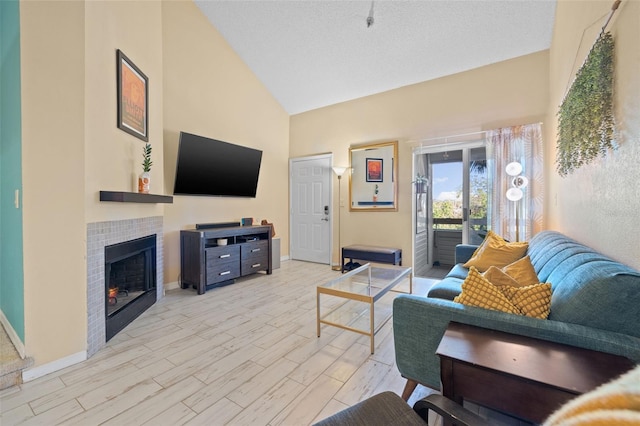 living room featuring a fireplace, light hardwood / wood-style flooring, high vaulted ceiling, and a textured ceiling