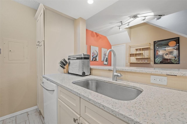 kitchen featuring light stone counters, white dishwasher, sink, electric panel, and lofted ceiling