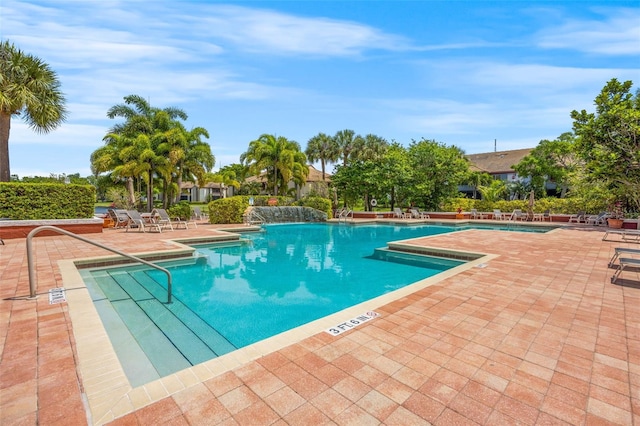 view of swimming pool with pool water feature and a patio area