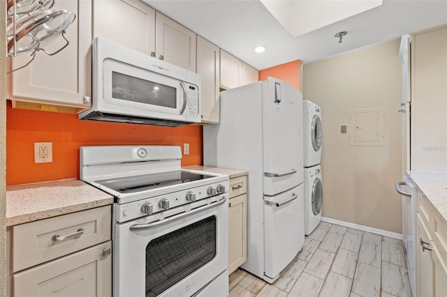 kitchen featuring light stone counters, stacked washer and dryer, and white appliances