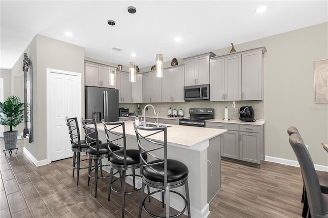 kitchen featuring a kitchen breakfast bar, dark wood-type flooring, decorative light fixtures, and appliances with stainless steel finishes