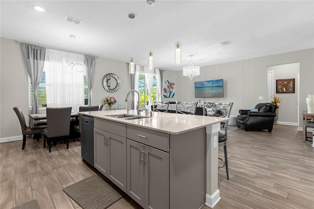 kitchen featuring gray cabinetry, sink, black dishwasher, an island with sink, and pendant lighting