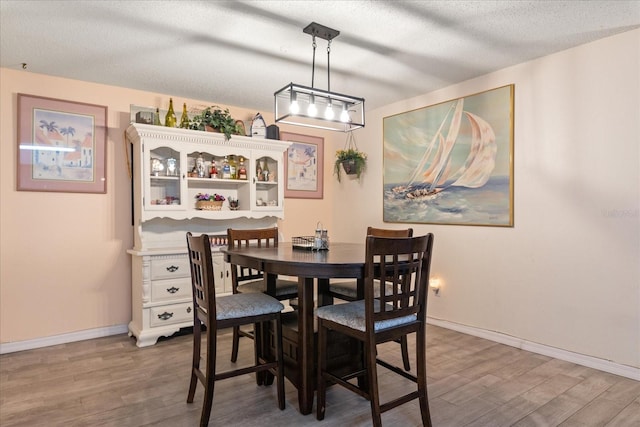 dining area with hardwood / wood-style floors and a textured ceiling