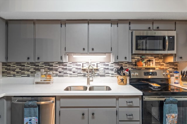 kitchen featuring backsplash, gray cabinetry, sink, and appliances with stainless steel finishes