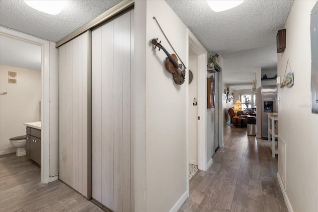 hall with wood-type flooring and a textured ceiling