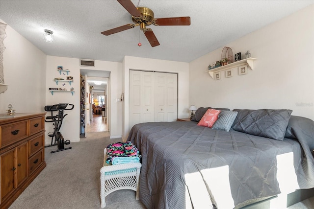 bedroom with a textured ceiling, light colored carpet, a closet, and ceiling fan