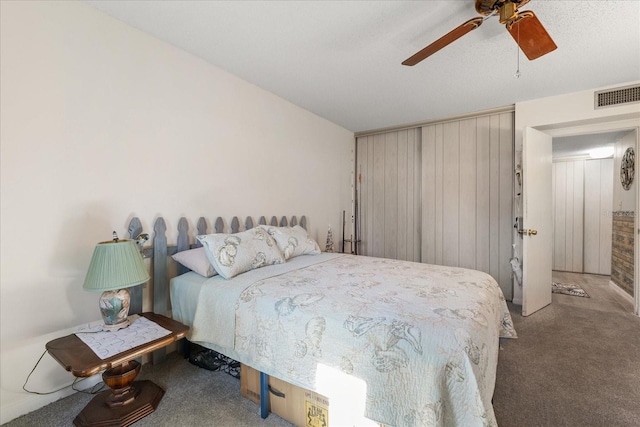 carpeted bedroom with ceiling fan and wooden walls