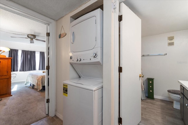 laundry area featuring stacked washer / drying machine, ceiling fan, a textured ceiling, and light hardwood / wood-style flooring