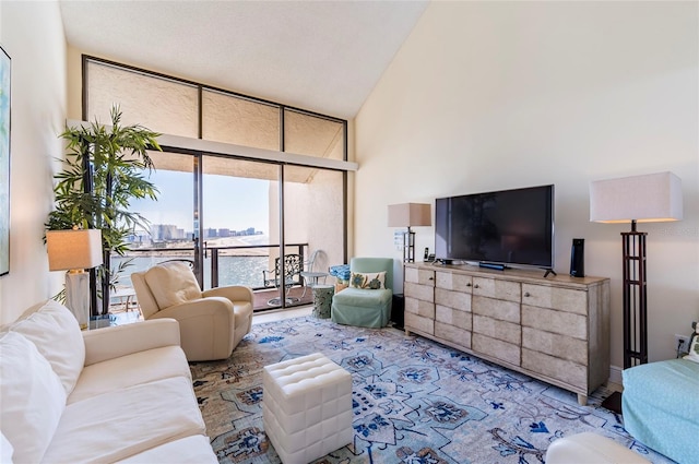 living room with high vaulted ceiling and a wall of windows